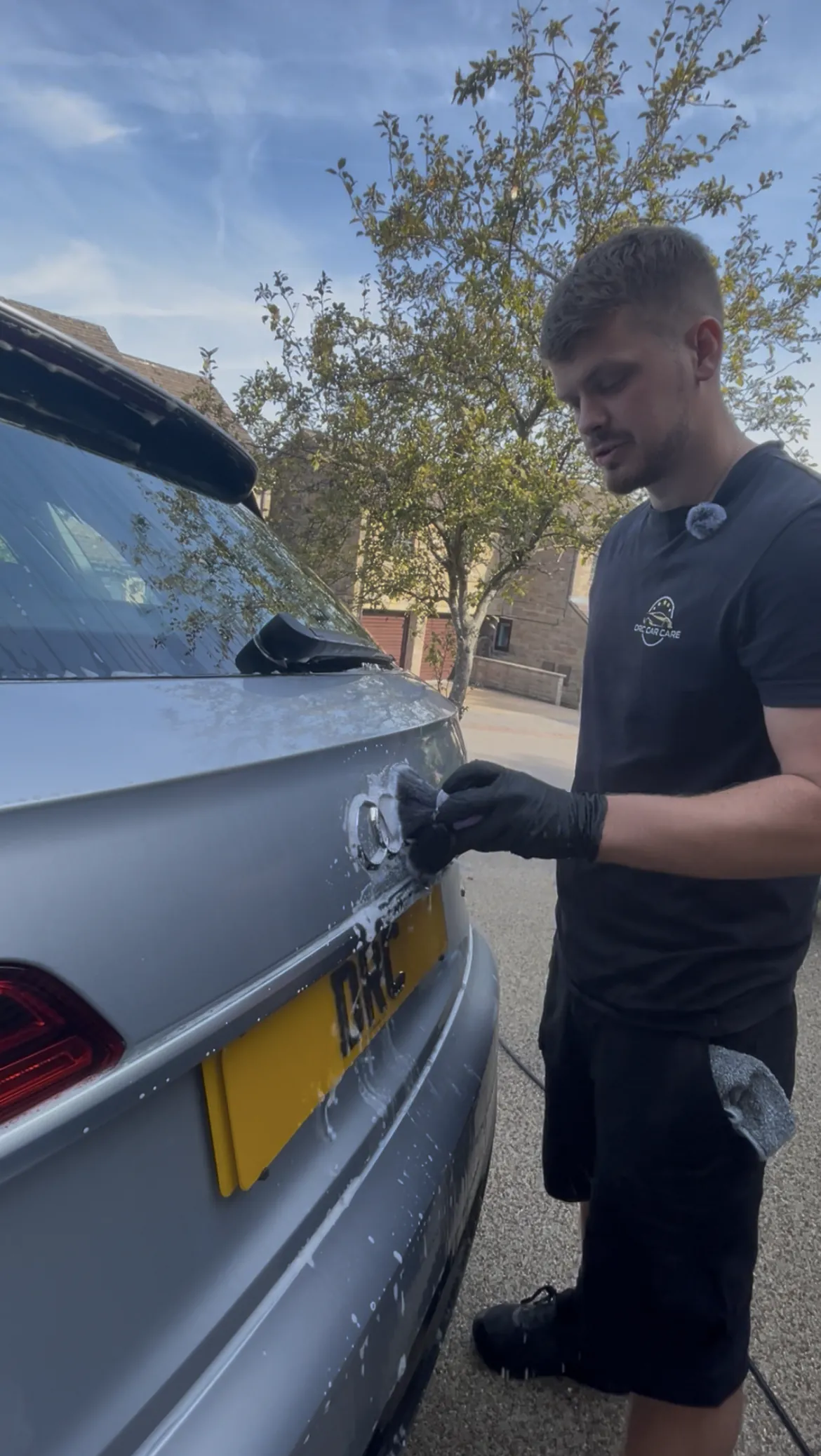 Cameron Duffy in a DRC Car Care t-shirt cleaning the rear badge of a silver car with a soft brush