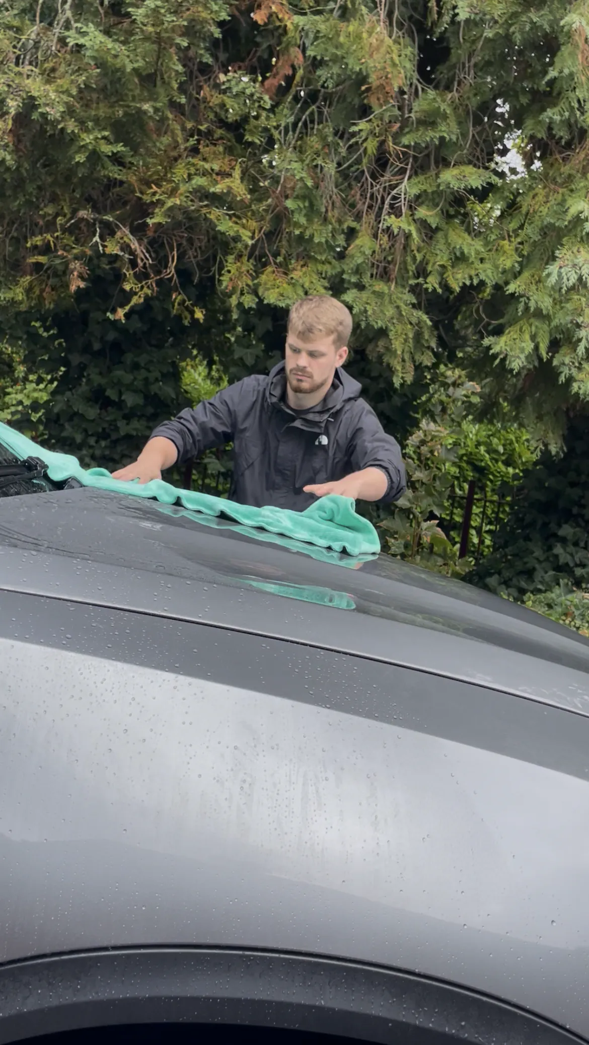 Cameron Duffy of DRC Car Care drying the roof of a grey car with a microfibre towel