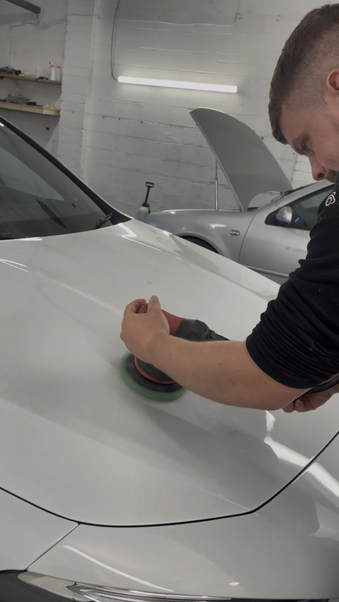 Cameron Duffy of DRC Car Care machine polishing the bonnet of a white car at the DRC Car Care unit